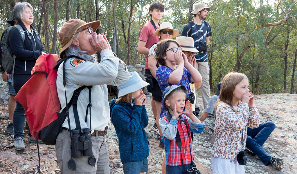 A ranger with a tour group of kids and families call out birdsongs in Warrumbungle National Park. Credit: Leah Pippos &copy; DCCEEW