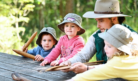 A NPWS Aboriginal ranger showing a group of kids clap sticks on a guided tour. Credit: Adam Hollingworth/DCCEEW &copy; DPE