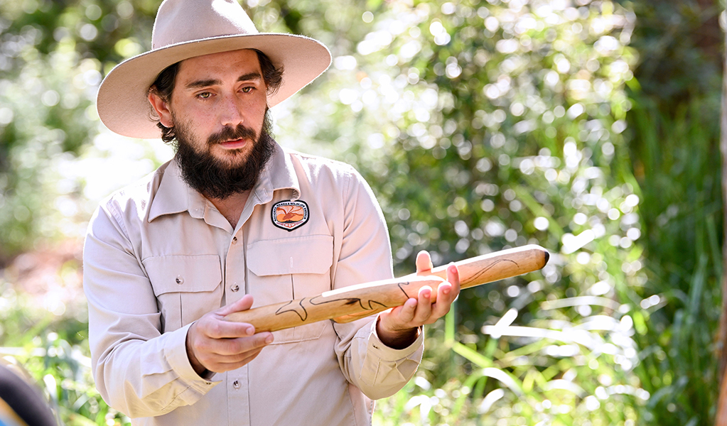 A NPWS Aboriginal ranger holding a clapping stick on a guided tour. Credit: Adam Hollingworth/DCCEEW &copy; DPE