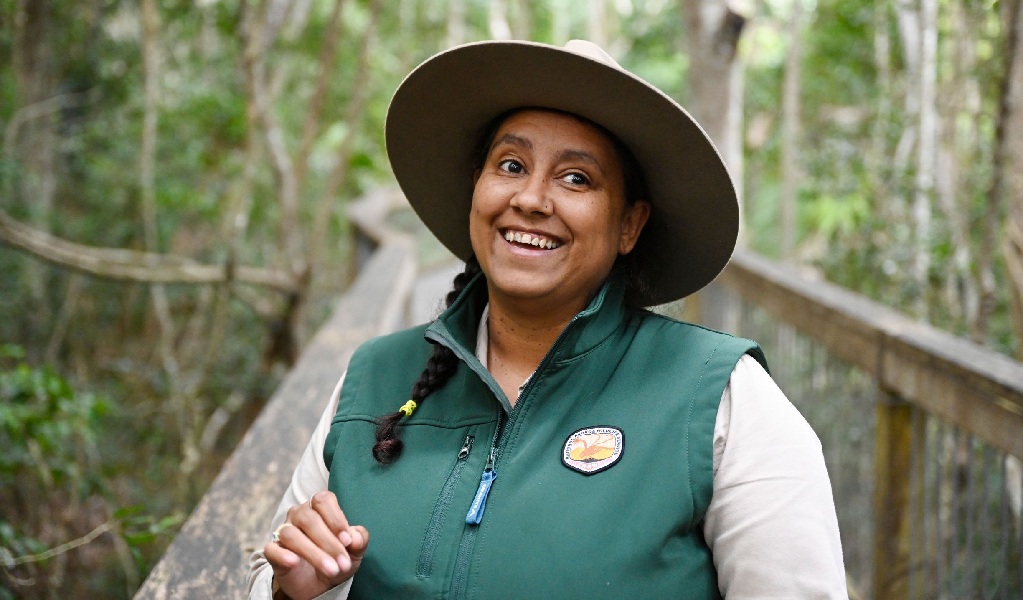 An Aboriginal Discovery ranger smiling to a tour group on the boardwalk at Sea Acres National Park. Credit: Adam Hollingworth &copy; DPE