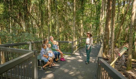 Family sitting, listening to a NPWS ranger on a guided tour of the Sea Acres National Park boardwalk. Credit: John Spencer &copy; DCCEEW