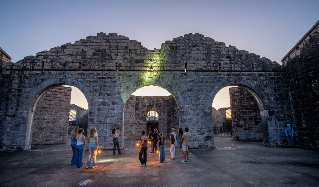 A group on a historical tour at sunset inside Trial Bay Gaol in Arakoon National Park. Credit: John Spencer &copy; DCCEEW