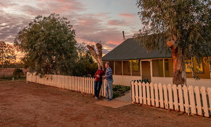 A couple watch an outback sunset outside Mount Wood Homestead, Sturt National Park. Photo: John Spencer/DPIE