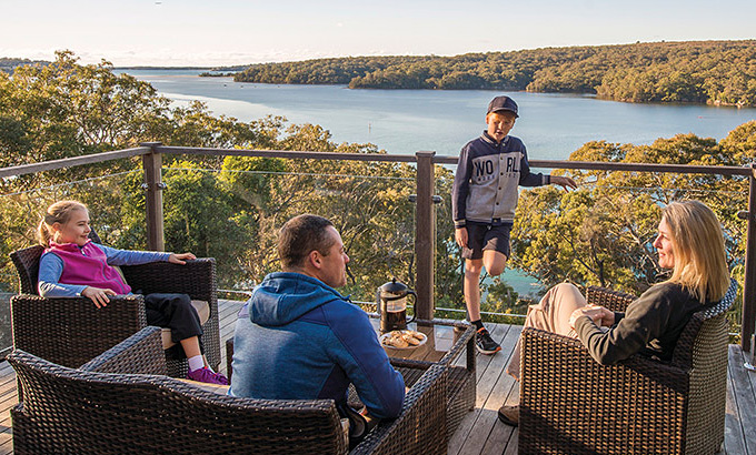 A family relax on the balcony at Hilltop Cottage, Royal National Park. Photo: John Spencer/DPIE