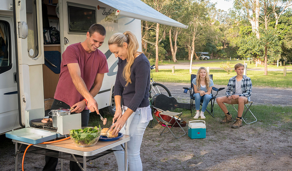 Campers cooking sausages on portable gas burner. Credit: John Spencer &copy; DCCEEW