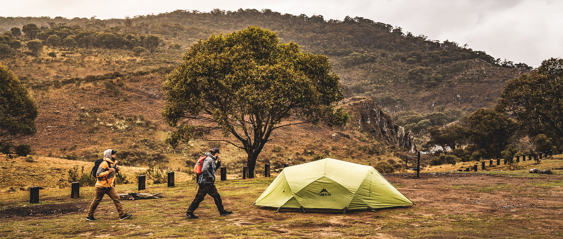 Two campers walk past a green tent at Blue Waterholes campground, Kosciuszko National Park. Photo: Robert Mulally/DCCEEW &copy; Robert Mulally