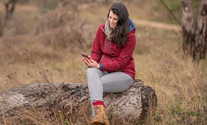 Visitor using a smartphone in an NSW national park. Photo credit: David Roma &copy; DPIE