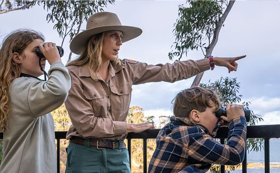 A ranger guiding 2 kids with binoculars on a tour in a national park. Credit: David Rogers/DCCEEW &copy; DCCEEW