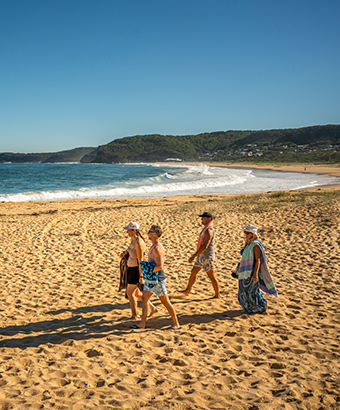 A group of people walking along Putty Beach in Bouddi National Park. Photo: John Spencer/DPIE