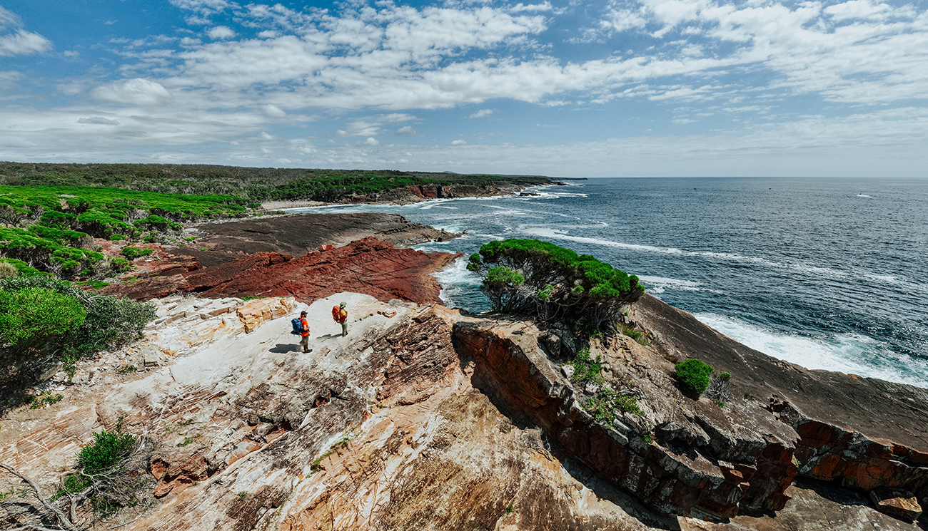 2 hikers on Pulpit Rock looking at the ocean from Light to Light Walk in Beowa National Park. Credit: Daniel Parsons/DCCEEW &copy; Daniel Parsons