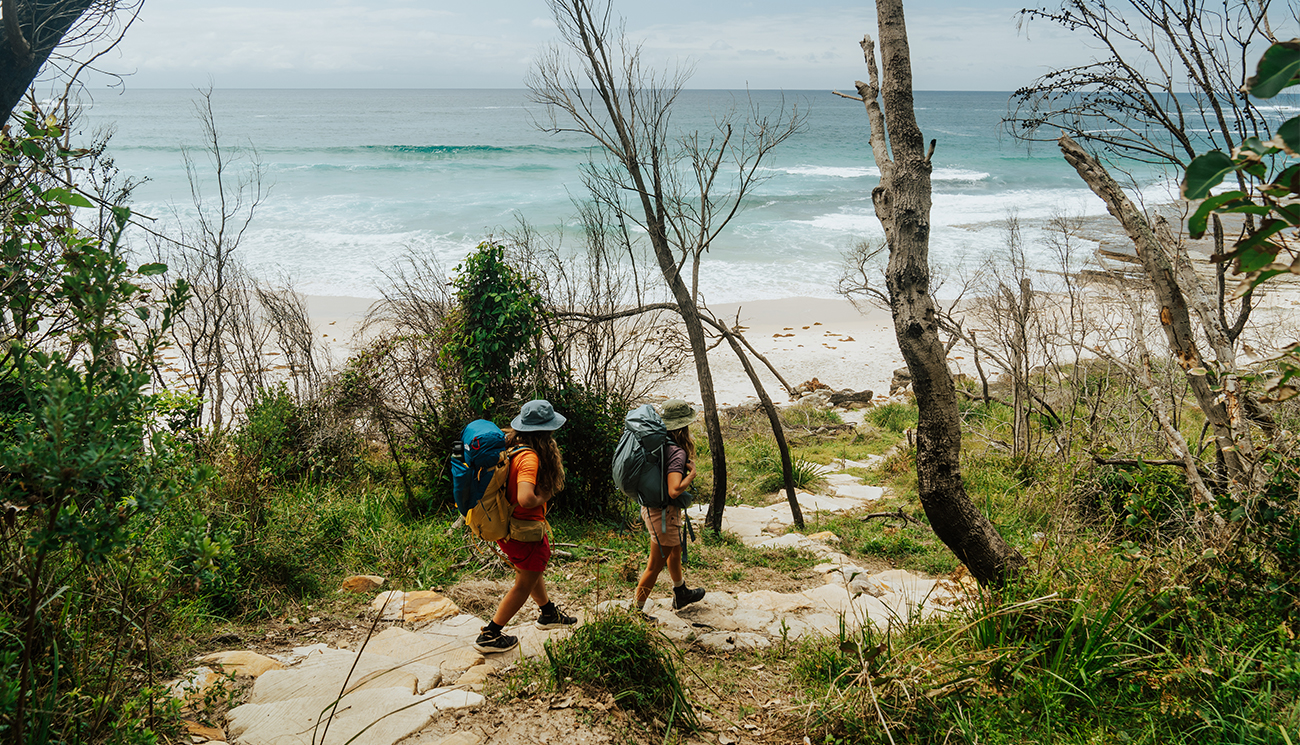 2 people on a walking track emerging from the bush towards the beach along Murramarang South Coast Walk. Credit: Remy Brand &copy; Remy Brand