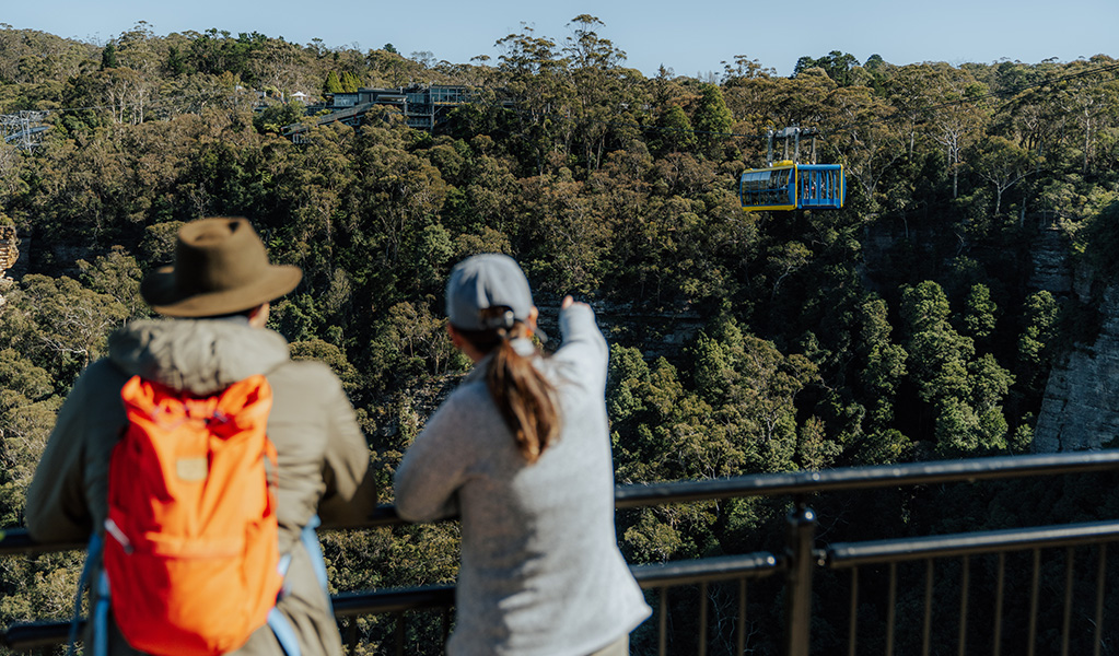 2 walkers watching Scenic World's Scenic Skyway as it passes over the valley below, Greater Blue Mountains Heritage Area. Photo: Remy Brand &copy; Remy Brand