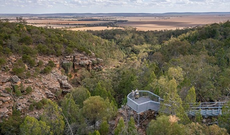 Two women stand at the steel railing of Jacks Creek lookout with views down into a gorge and expansive views out across country. Credit: John Spencer &copy; DCCEEW