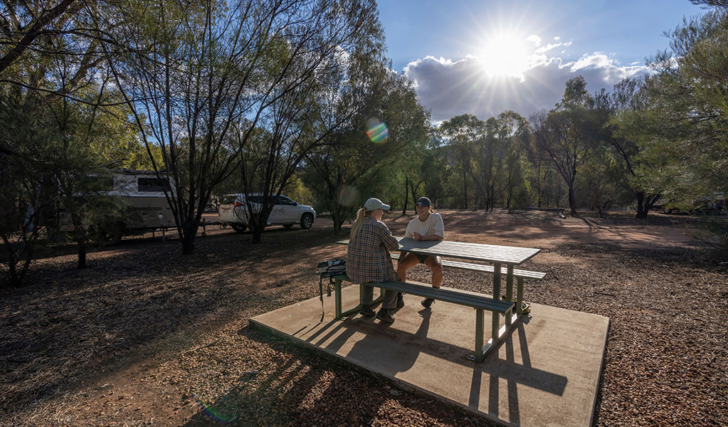 Two people sitting at the picnic table at Woolshed Flat campground in Cocoparra National Park. Credit: Jonh Spencer &copy; DCCEEW