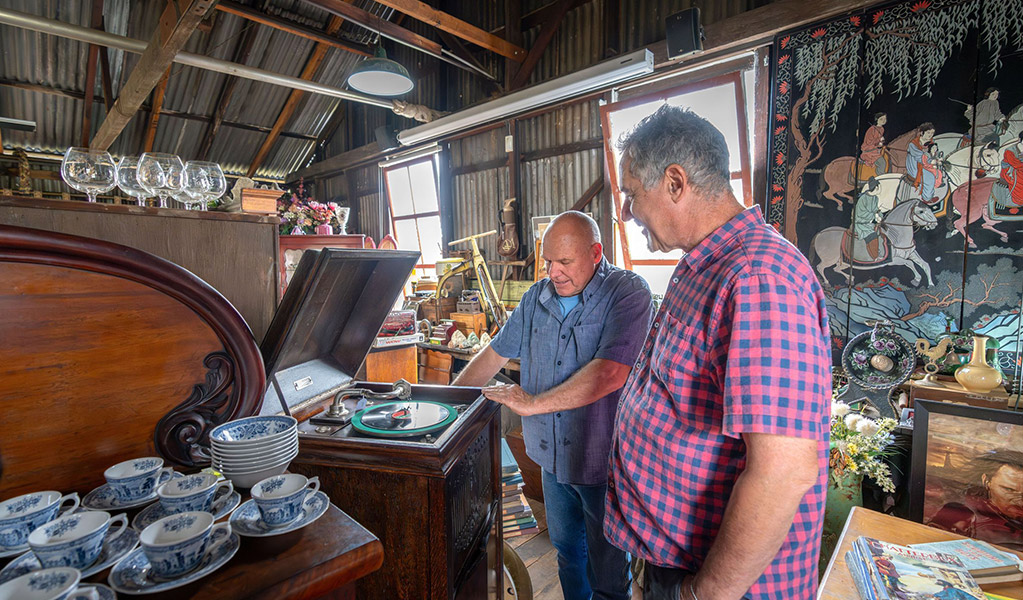 2 people looking at an antique record player inside Gold Rush Antiques at Hartley Historic Site. Credit: John Spencer &copy; DCCEEW