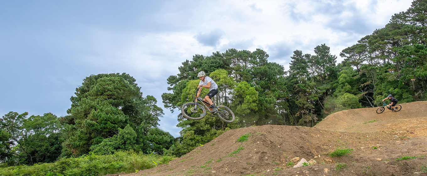 Rider gets air off a jump on Kembla mountain bike trails. Credit: John Spencer &copy; DCCEEW