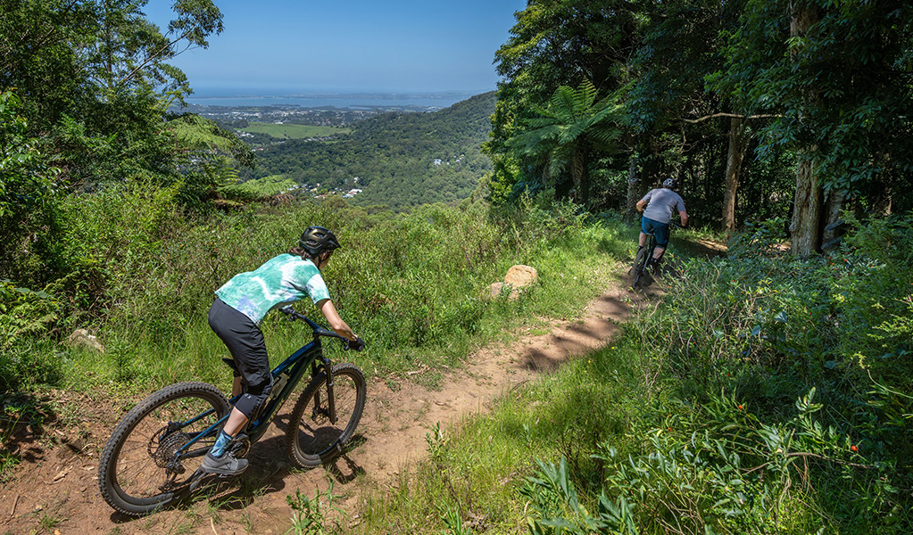 Two riders on Kembla mountain bike trails with incredible views over the escarpment down to the ocean. Credit: John Spencer &copy; DCCEEW