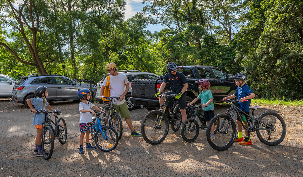 Two dads with 4 young kids on bikes set off from the carpark for a big day of riding. Credit: John Spencer &copy; DCCEEW