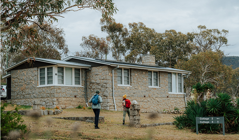 2 hikers standing outside a cottage at Creel Bay near Snowies Alpine Walk. Credit: Remy Brand / DCCEEW &copy; Caravel Content