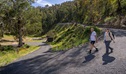 Two people walking down Yarrangobilly Thermal Pool walk, a short but steep bitumen road down to the pool. Credit: John Spencer &copy; DCCEEW