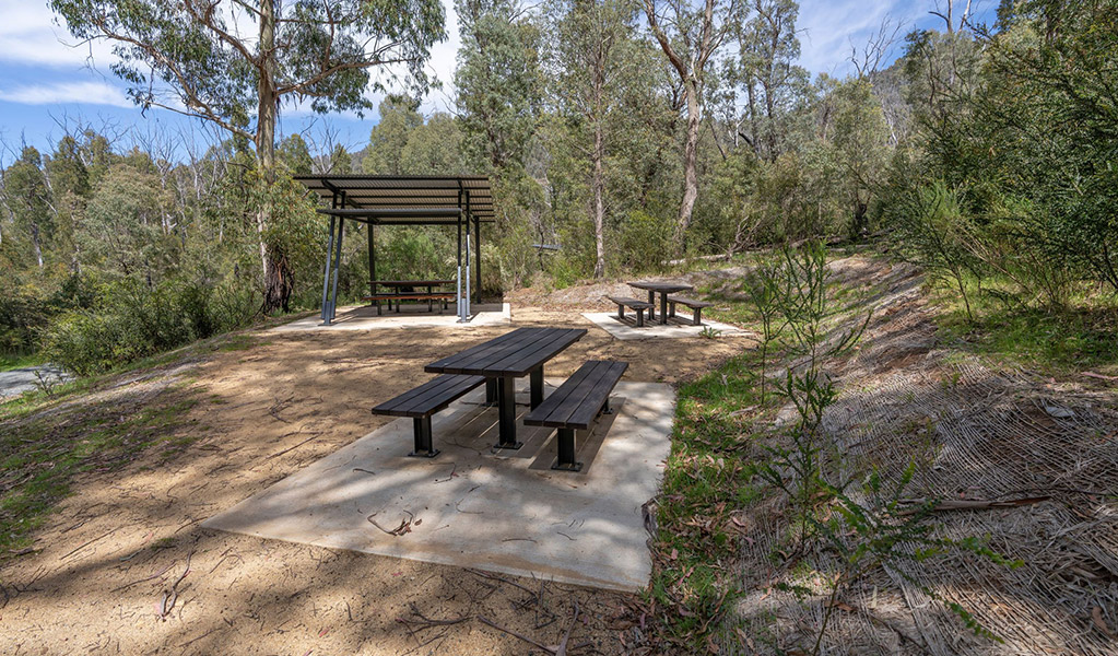 Open and shaded picnic tables at the picnic area surrounding Yarrangobilly Caves thermal pool. Credit: John Spencer &copy; DCCEEW