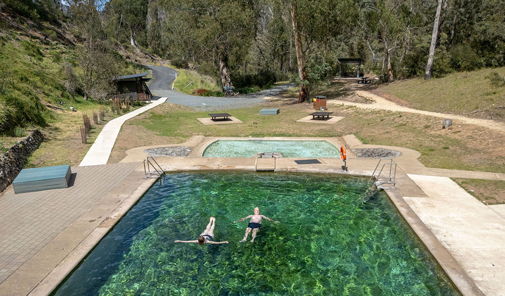 Two people in Yarrangobilly Caves thermal pool next to the small kids pool. Credit: John Spencer &copy; DCCEEW