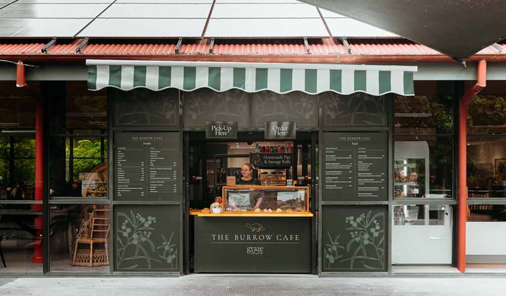 Exterior counter of The Burrow Cafe, with chalk menus and a staff member, Morton National Park. Credit and &copy;: Lily Crouch