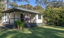Guest on the verandah, Depot Beach cabins. Photo: John Spencer &copy; DCCEEW
