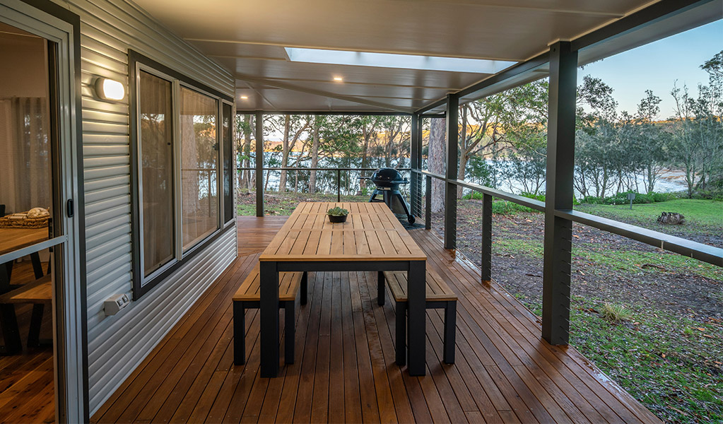 Judges House covered verandah with dining table, seating and a water view. Photo: John Spencer &copy;DPIE