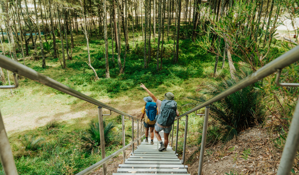 2 bushwalkers descending a set of metal stairs at Maloneys Beach, Murramarang South Coast Walk. Credit: Remy Brand &copy; Remy Brand