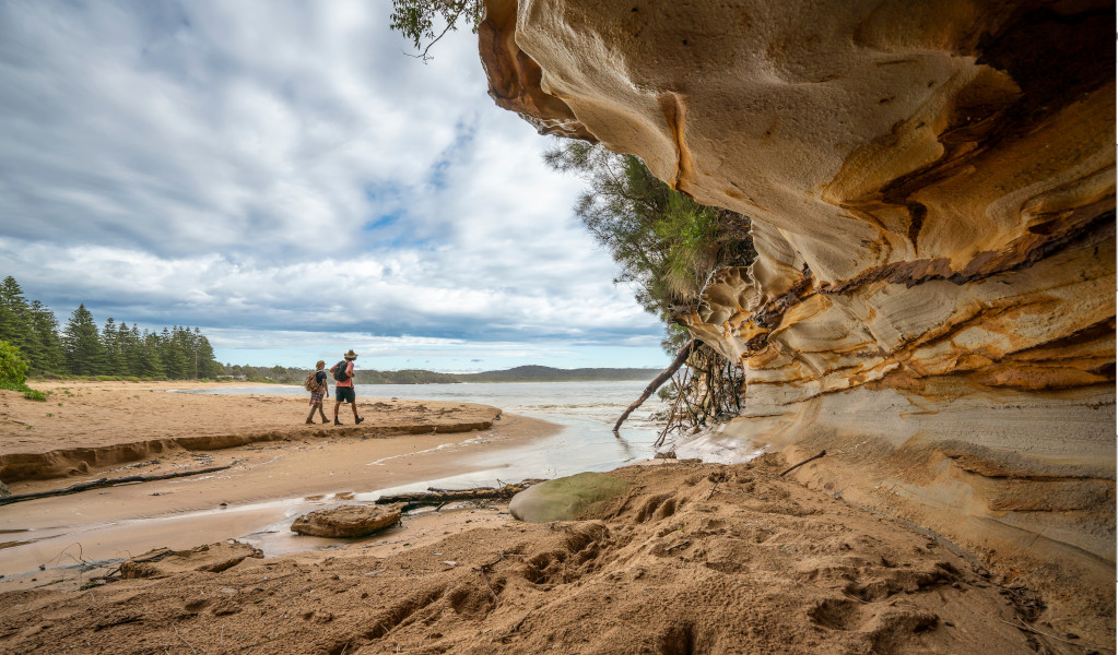 2 people walking past a sandstone rock feature on the Murramarang South Coast Walk. Credit: John Spencer &copy; DPE