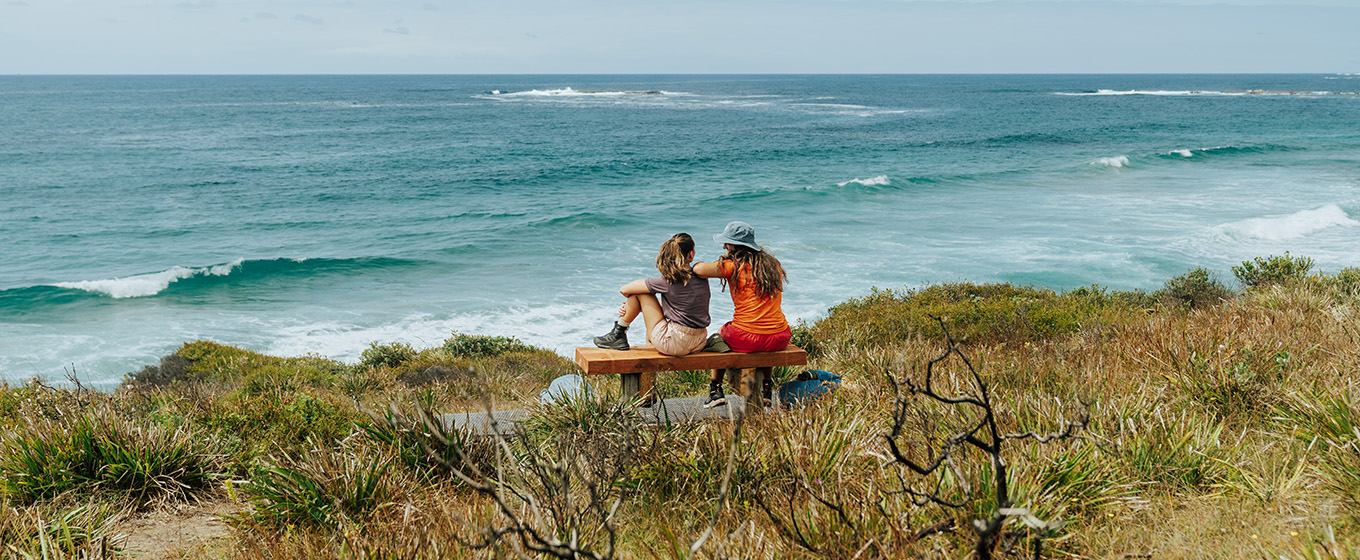 2 walkers sitting on a bench on the walking track between Pretty Beach and Pebbly Beach, watching the sea. Credit: Remy Brand &copy; Remy Brand