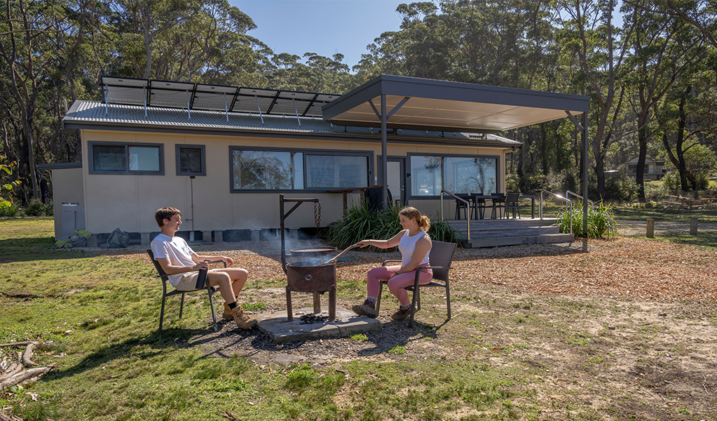 Guests cooking outside Jack's shack, Pebbly Beach. Photo: John Spencer &copy; DCCEEW