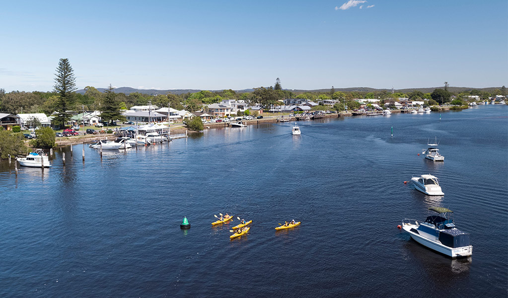 Aerial view of kayaking on the Myall River, Tea Gardens with township and foreshore in the background. Credit: Craig Parry &copy; Destination NSW