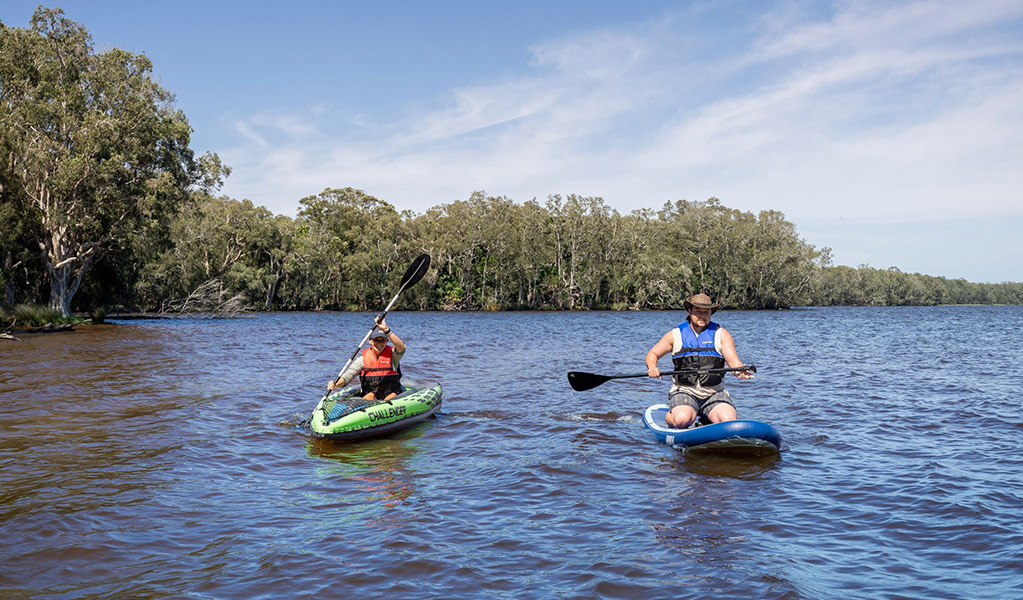 A person on a kayak and a person on a paddle board on Myall Lakes in Myall Lakes National Park. Credit: John Spencer/DCCEEW &copy; DCCEEW
