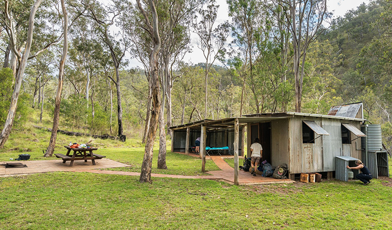 Tiny, timber Colwells Hut with a seperate building for camper stretchers and an outdoor picnic table. Credit: David Waugh &copy; DCCEEW