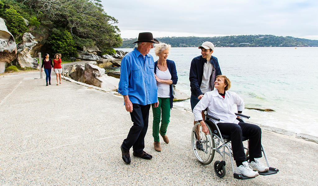 Wheelchair user admiring views of Shark Beach from the wheelchair accessible path in Nielsen Park. Credit: Simone Cottrell © DCCEEW