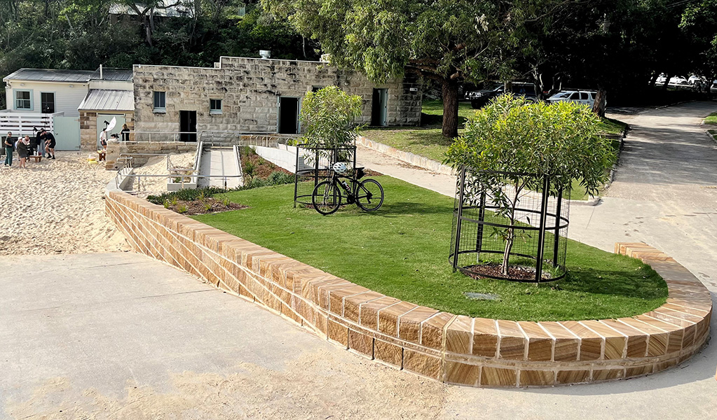 An accessible ramp from the promenade to Shark beach and accessible toilets in the sandstone building behind it. Photo: Natasha Webb © DCCEEW