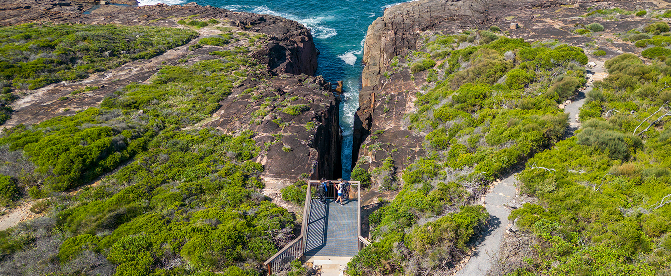 Aerial photo of Slot canyon lookout, perched over the a gap in the cliffline above the ocean. Credit: John Spencer &copy; DPE