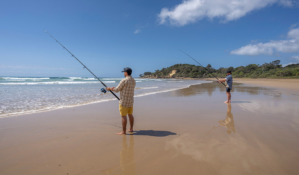 Two people fishing from the sand on Illaroo-Sandon Beach. Credit: John Spencer &copy; DCCEEW